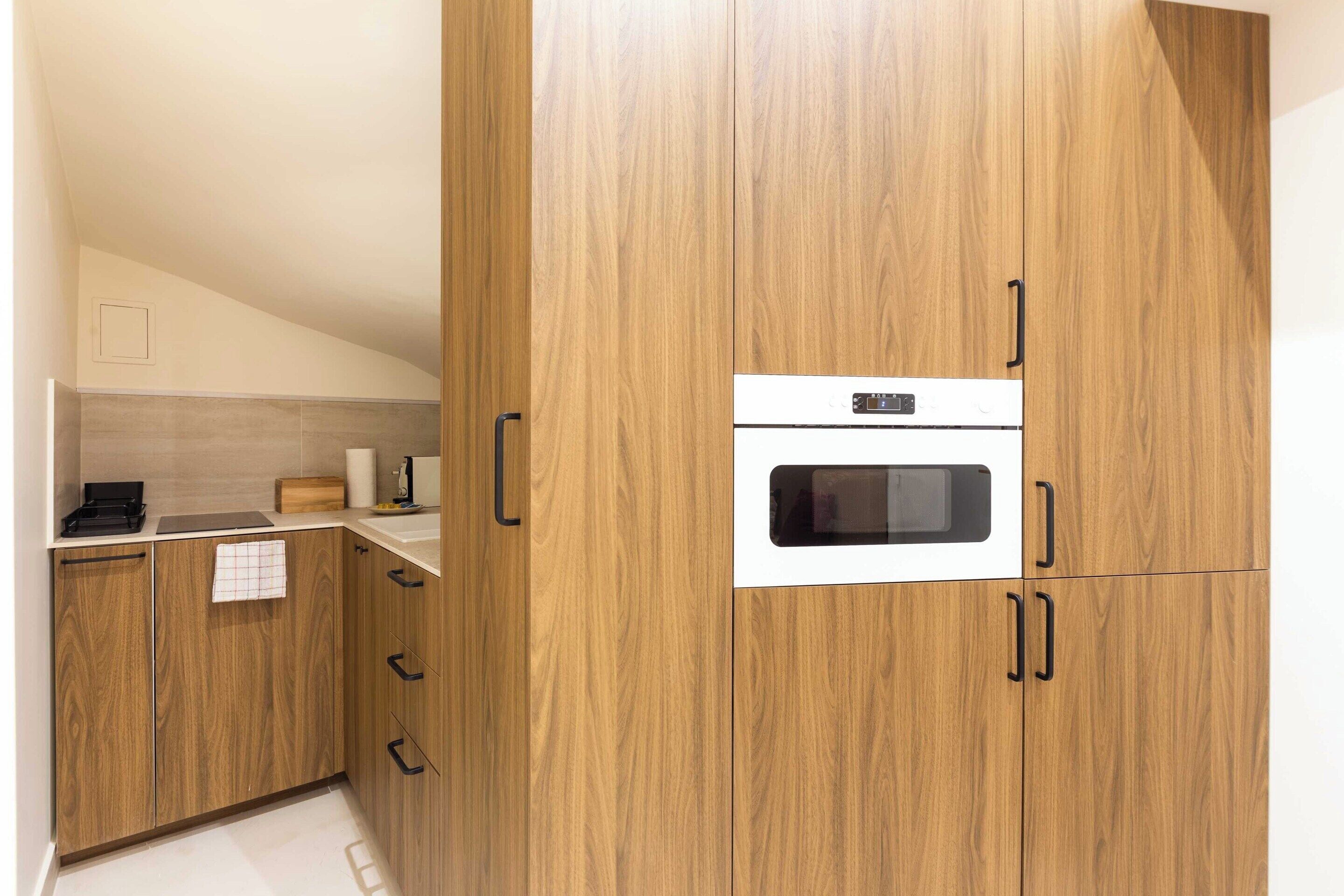 Une cuisine avec des meubles de rangement en bois, un four à micro-ondes et un plan de travail sur lequel se trouve une bouilloire.