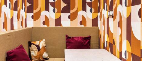 A corner seating area with a sofa and a small table, surrounded by a patterned wall.
