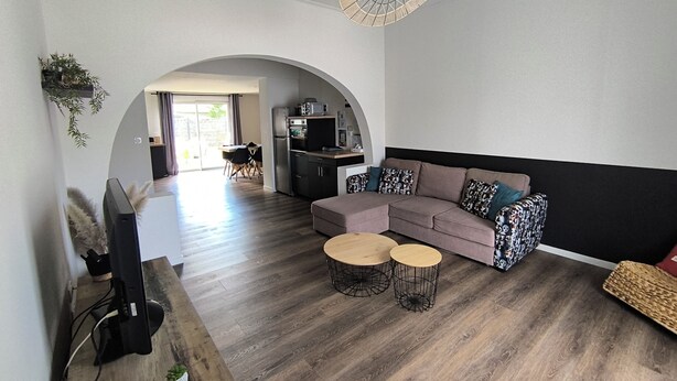 A modern living room with a sectional sofa, two round coffee tables, a flat-screen TV, and a unique ceiling fan. - Vacation home - 9 people - "Relax à Sion" between sea and forest (Saint-Hilaire-de-Riez)