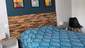 A bedroom with a wooden headboard, a bed with a blue and white polka dot bedspread, a nightstand with a lamp, and three framed pictures on the wall. - Vacation home - 9 people - "Relax à Sion" between sea and forest (Saint-Hilaire-de-Riez)