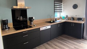 A modern kitchen with black cabinets, a wooden countertop, a built-in oven, and a coffee machine. - Vacation home - 9 people - "Relax à Sion" between sea and forest (Saint-Hilaire-de-Riez)