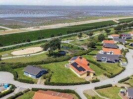 Vista aérea de uma área residencial com casas, uma estrada e uma praia ao fundo.