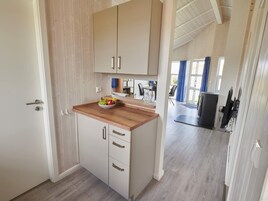 A modern kitchen with wooden cabinets, a wooden countertop, and a bowl of fruit.