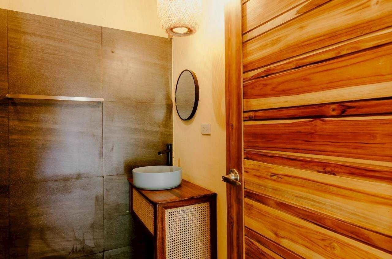 A bathroom with a wooden vanity, a round mirror, and a white sink.