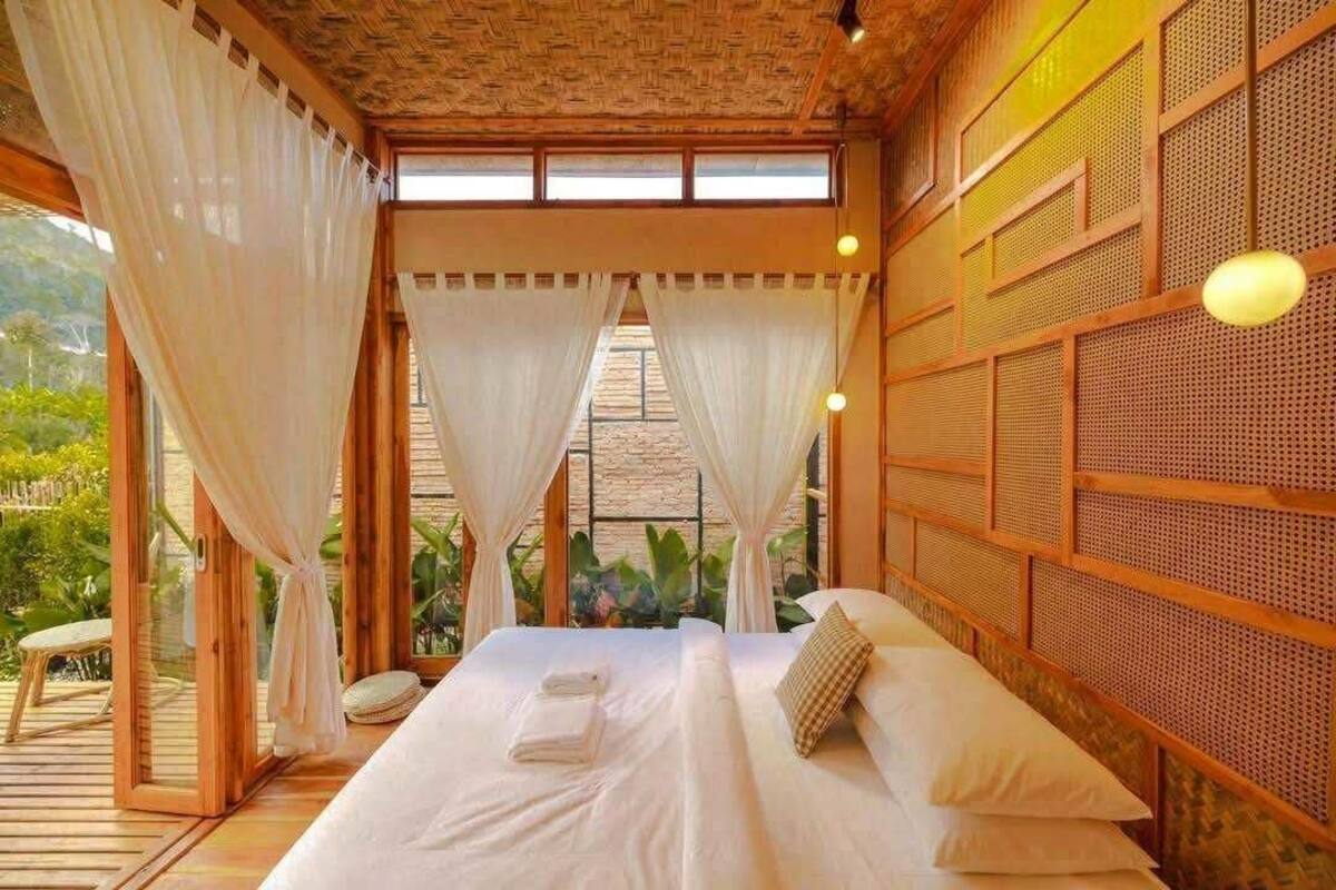Une pièce avec un lit, des rideaux blancs et un plafond en bois.