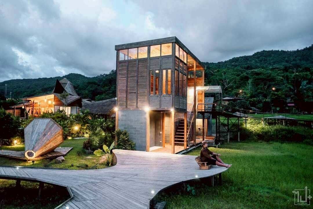 Un'accogliente baita di legno moderna, su più livelli, con ampie finestre a vetro, immersa nel verde e con un'elegante terrazza in legno.