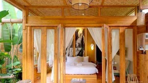 A wooden room with a bed, curtains, and a hanging light fixture.