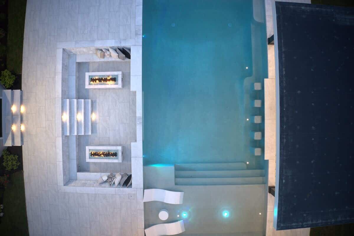 Una piscina en la azotea con zona de estar, escalones de acceso y una sección cubierta.