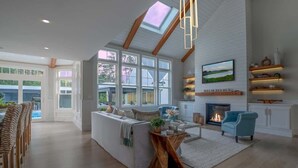 Un soggiorno spazioso con soffitto alto, ampie finestre, un caminetto e una zona salotto accogliente.