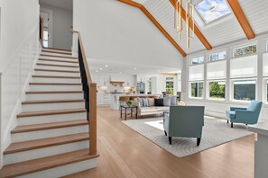 A spacious living area with a staircase, a kitchen, and large windows. - Dennis Family Oasis: Pool, Hot Tub, & Fire Pit! (Dennis)