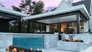 Una zona relax esterna moderna con piscina, braciere e posti a sedere.