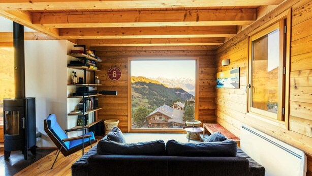 A cozy cabin interior with a wooden ceiling, a sofa, a bookshelf, and a large window offering a mountain view. - Chalet, view mountain, fireplace or stove, parking, tv, ski locker, 125m², Vars (Vars)