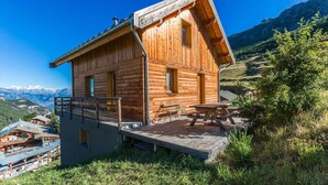 A wooden cabin with a deck and picnic tables, set against a mountainous backdrop. - Chalet, view mountain, fireplace or stove, parking, tv, ski locker, 125m², Vars (Vars)