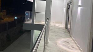 A modern building exterior at night with a glass elevator, metal railings, and a marble floor. - Alojamento Santos Silva  (São Tomé)