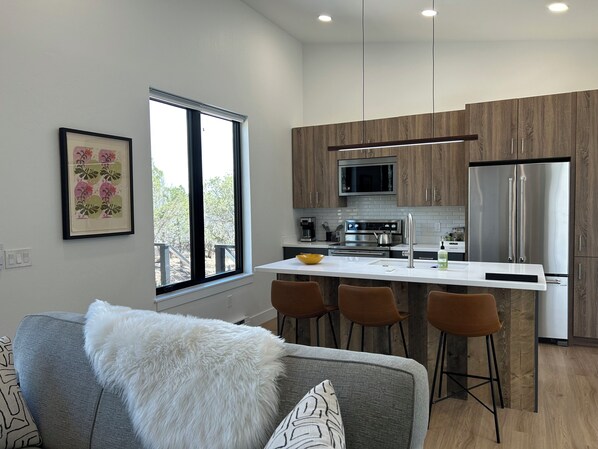 A modern kitchen with a central island, stainless steel appliances, and wooden cabinetry.