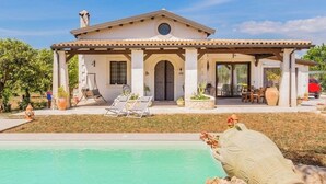 A Mediterranean-style villa with a pool, outdoor seating, and a covered patio.