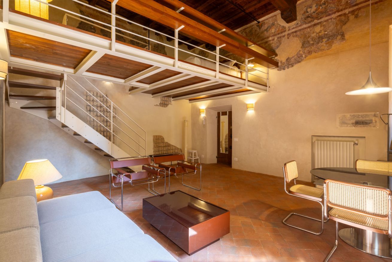 A spacious living area with a staircase, a dining table with chairs, a sofa, and a coffee table.