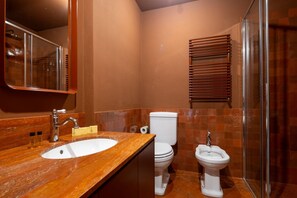 Un baño con lavamanos de mármol, inodoro, bidé y ducha.