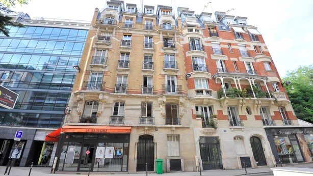 A multi-story building with a mix of modern and classic architectural styles, featuring balconies and large windows.