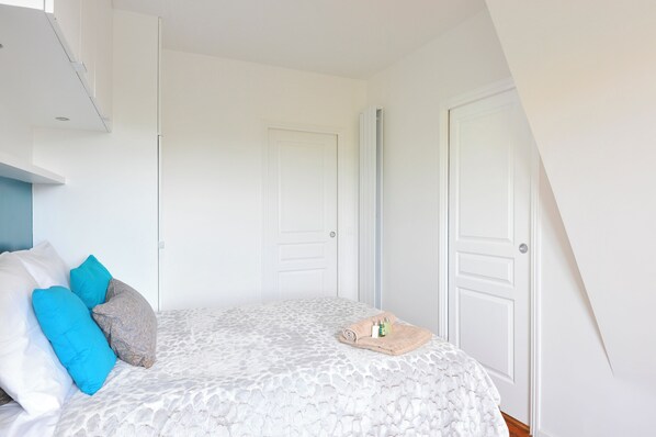 Un dormitorio con cama, almohadas, una toalla enrollada y artículos de aseo.