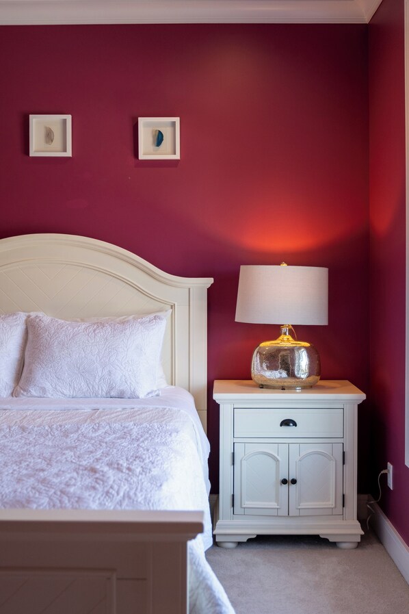 A bedroom with a bed, a nightstand with a lamp, and two framed pictures on the wall.