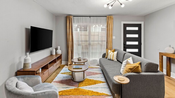 A modern living room with a flat-screen TV, grey sofa, and a coffee table.