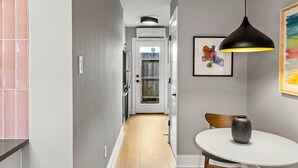 A modern kitchen with white cabinets, a wooden floor, and a dining area with a white table and a vase.