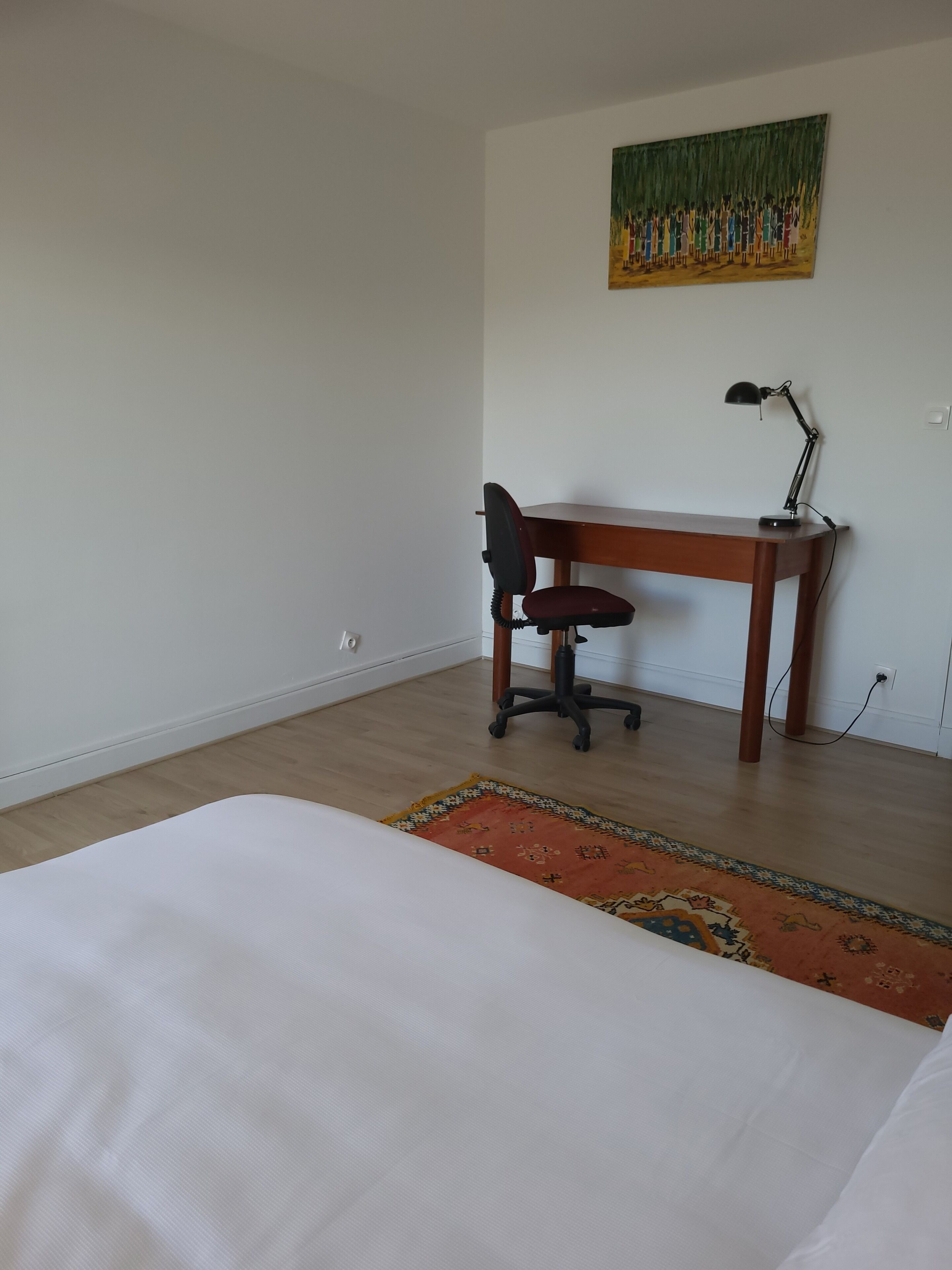 Un dormitorio con una cama, un escritorio, una silla y un cuadro en la pared.