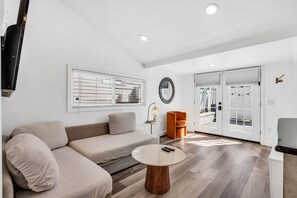 A modern living room with a sofa, a round coffee table, and a TV mounted on the wall.