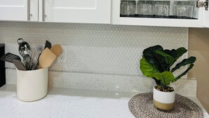 A kitchen with white cabinets, a spice rack, and a potted plant on the countertop. - Meet. Play. Stay. • Relax & Play in Orlando (Orlando)