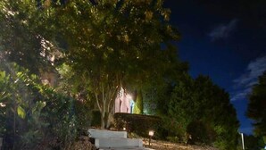Una scalinata esterna illuminata di notte, con gradini che conducono a un edificio, circondata da alberi e vegetazione.