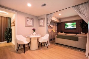 A modern living room with a sofa, a TV, and a dining area with chairs and a table.