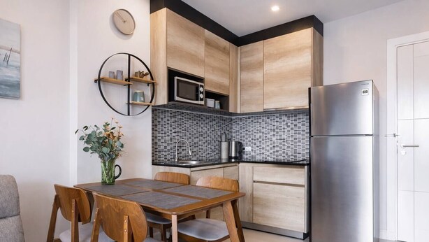 Eine moderne Küche mit Holzausstattung, einem Edelstahlkühlschrank und einem Essbereich mit Tisch und Stühlen.