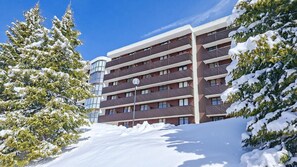 Un hotel de varios pisos con balcones, rodeado de árboles cubiertos de nieve.