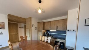 A modern kitchen with wooden cabinets, a stainless steel sink, and a round dining table with chairs. - 250m from ski slopes, 1st floor, view resort, terrace, parking, tv, ski locker, 53m², Les Saisies (Villard-sur-Doron)