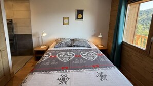 A bedroom with a bed, two bedside lamps, a wall-mounted shelf, a window with curtains, and a ceiling light fixture. - 250m from ski slopes, 1st floor, view resort, terrace, parking, tv, ski locker, 53m², Les Saisies (Villard-sur-Doron)