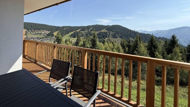 A balcony with a wooden railing, two chairs, and a table. - 250m from ski slopes, 1st floor, view resort, terrace, parking, tv, ski locker, 53m², Les Saisies (Villard-sur-Doron)