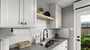 Eine moderne Küche mit weißen Schränken, einer Edelstahl-Spüle und einem Holzboden.
