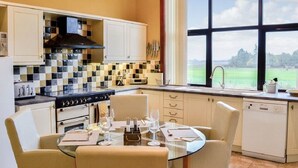 Une cuisine avec un crédence à carreaux, une cuisinière et un coin repas avec une table mise pour deux personnes.