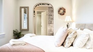Une chambre à coucher avec un lit, un miroir, une bibliothèque, une lampe et une guirlande décorative accrochée au mur.