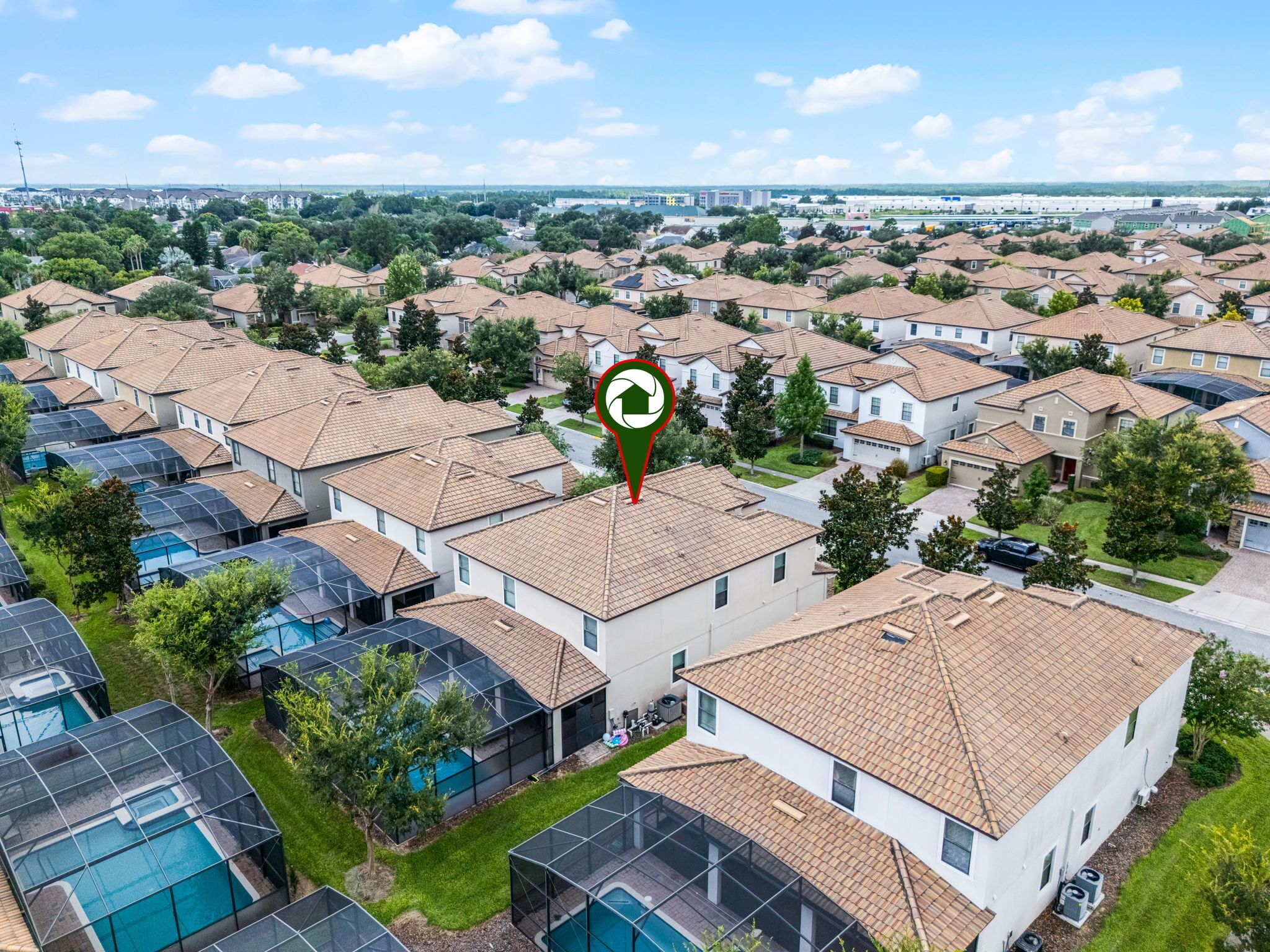 A residential area with multiple houses, some with solar panels, and a clear sky.
