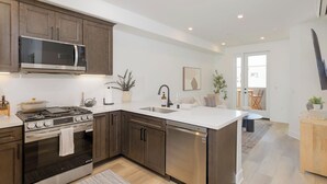 A modern kitchen with stainless steel appliances, wooden cabinets, and a white countertop. - Coastal Getaway with Ocean Views (Grover Beach)