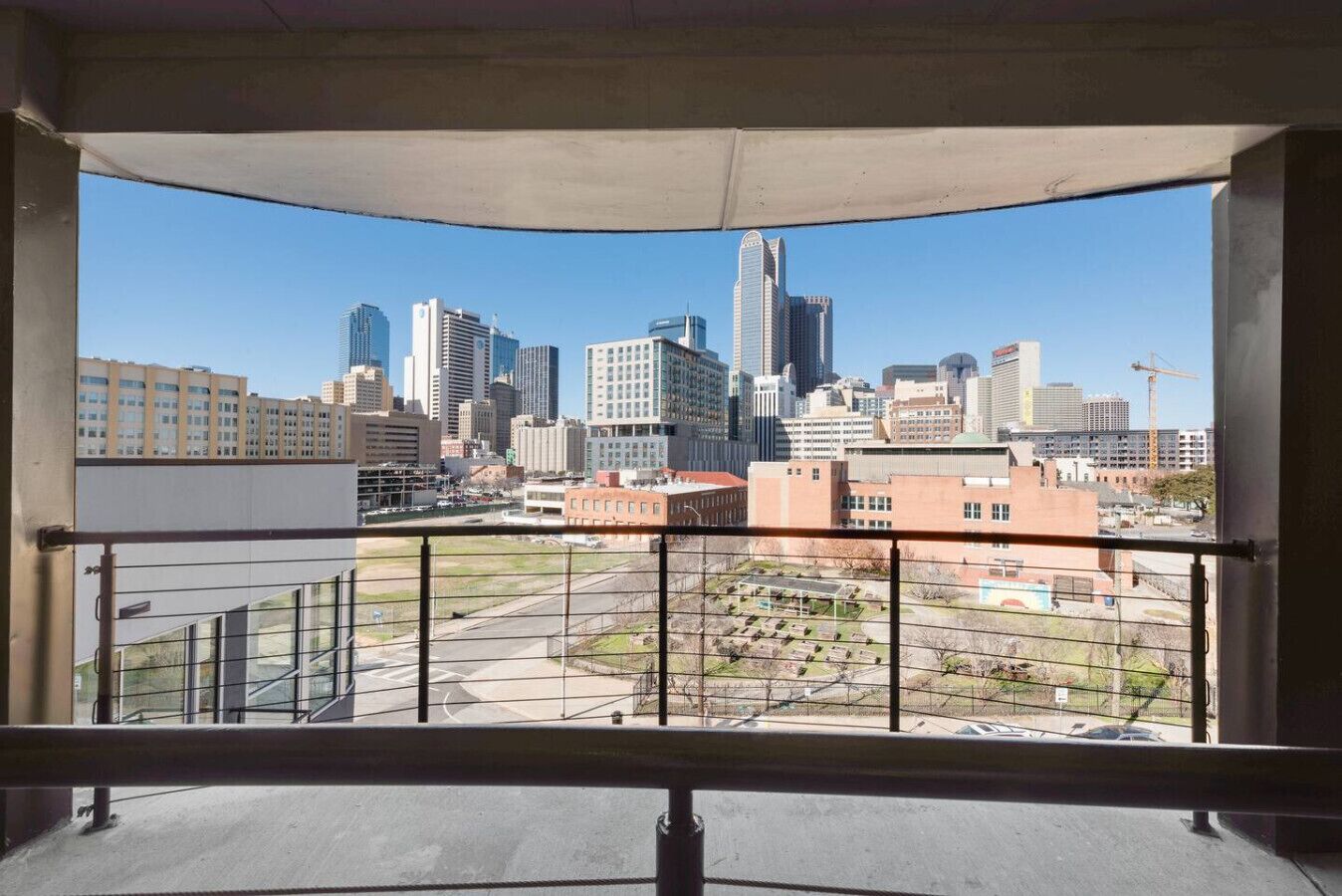 A view from a balcony with a cityscape, including high-rise buildings and a construction site.