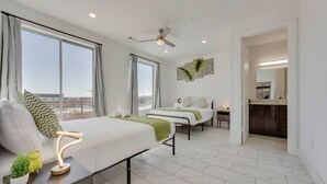 Habitació d'hotel moderna amb dos llits, un finestral gran, un ventilador de sostre i vista a la ciutat.