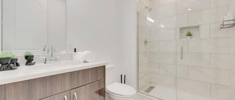 A modern bathroom with a wooden vanity, white sink, and a glass shower enclosure.