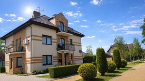 A two-story residential building with a balcony, a chimney, and a paved driveway. - Apartment in Miedzywodzie With a Swimming Pool (Dziwnów)