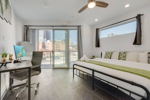Habitación de hotel moderna con cama, escritorio, silla y vista a la ciudad por la ventana.