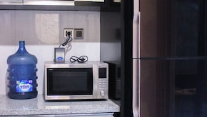 Una cocina equipada con microondas, dispensador de agua y refrigerador.