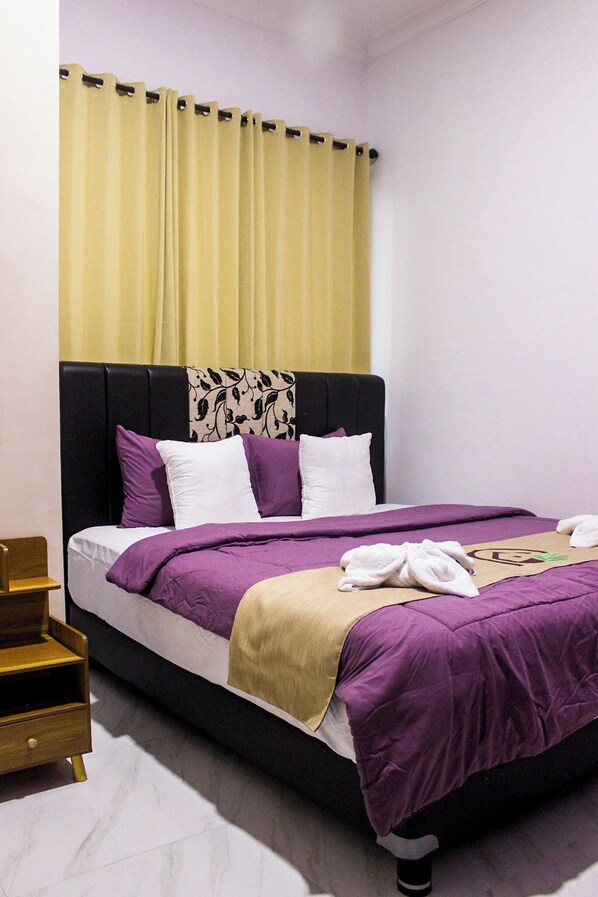 A neatly made bed with a black headboard, purple and white bedding, and a yellow curtain. - Omah Poer Banyuwangi (Banyuwangi)