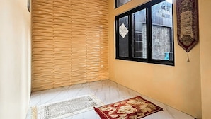 Una habitación con piso de mármol, pared con textura de madera, ventana con vidrio decorativo y una placa en la pared.